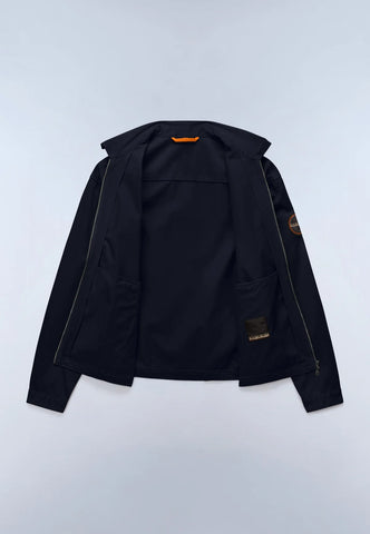 A black zip-up jacket with a high collar, laid flat against a light gray background. It features a small orange accent at the inner collar and a circular patch on the left sleeve.