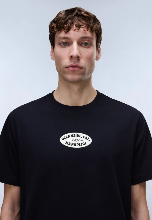 Person wearing a black t-shirt with a logo on a plain background