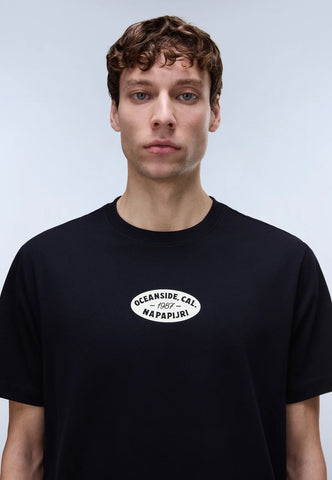 Person wearing a black t-shirt with a logo on a plain background