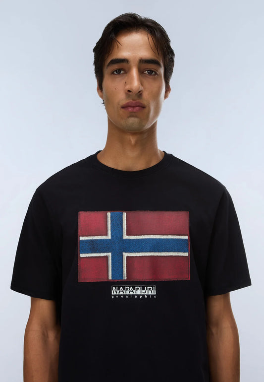 A man wearing a black crewneck t-shirt featuring a large rectangular graphic of the Norwegian flag on the chest, with 'NAVFRI' printed below it, set against a light gray studio background.
