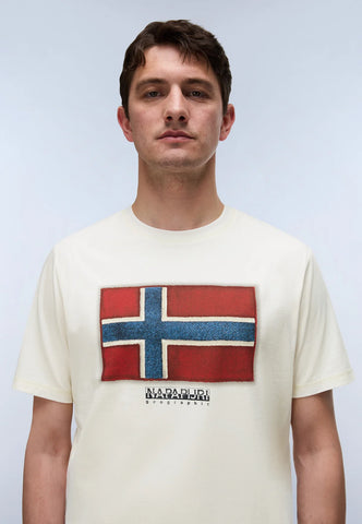 A man wearing a cream-colored t-shirt with a distressed graphic of the Norwegian flag and the brand name 'NORDAGARI' printed below it, set against a light gray studio background.