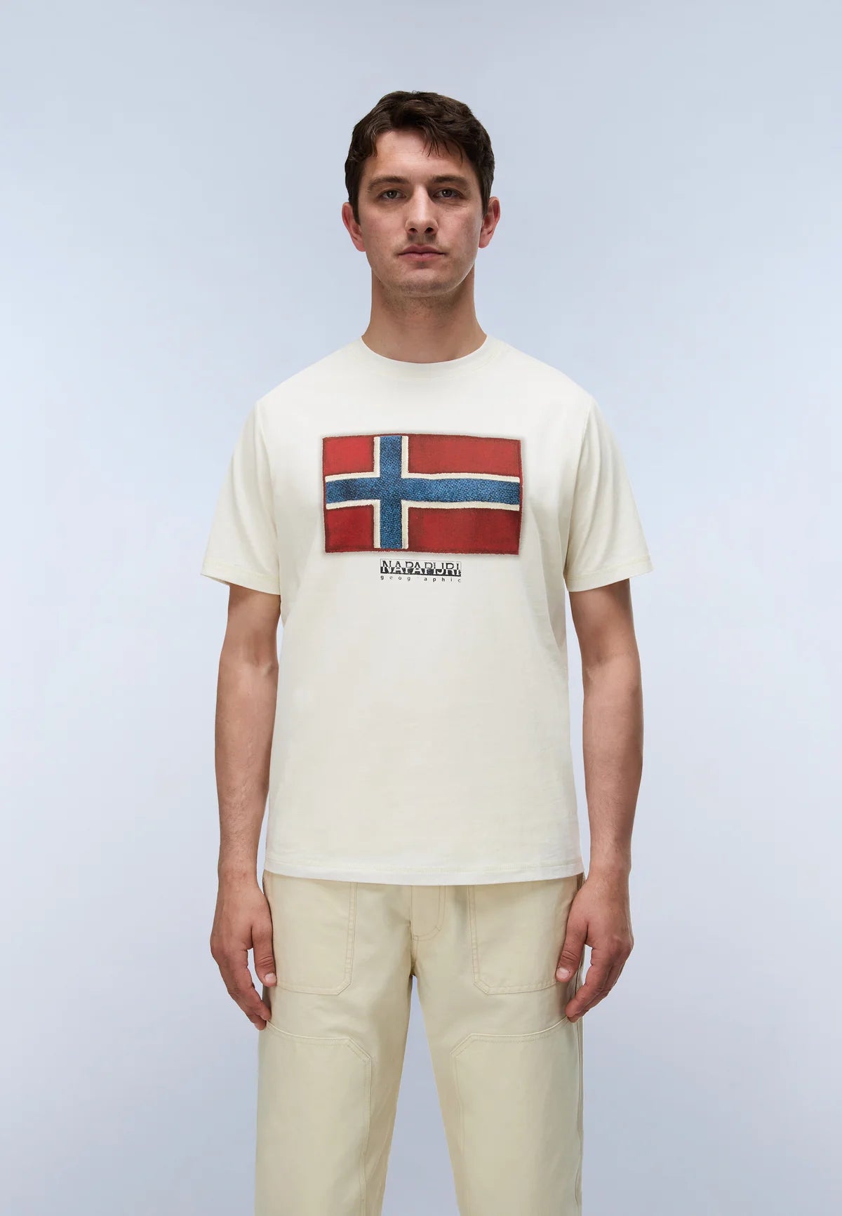 Man wearing a white t-shirt with a red and blue flag design on a light gray background