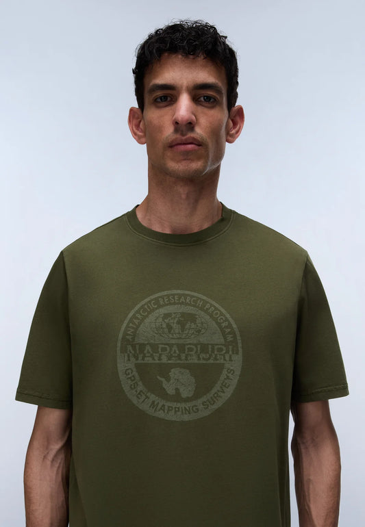 A man wearing an olive green crewneck t-shirt with a faded circular graphic on the chest that reads 'NAPA PULI NATIONAL PARK GREAT MAPPING SURVEY'.