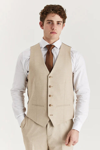 Man wearing a beige vest over a white shirt with a brown tie on a light gray background