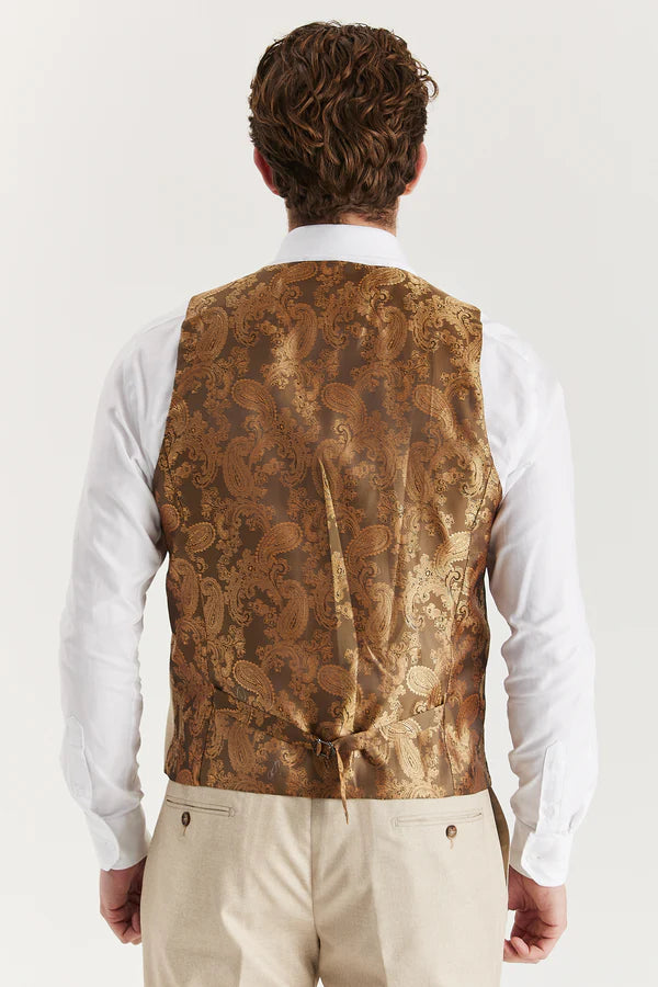 Man wearing a patterned vest over a white shirt on a plain background