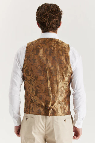 Man wearing a patterned vest over a white shirt on a plain background