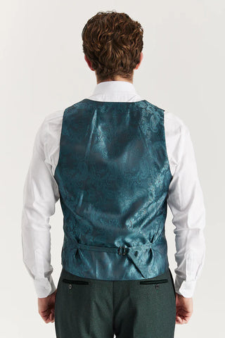Man wearing a teal vest over a white shirt on a plain background