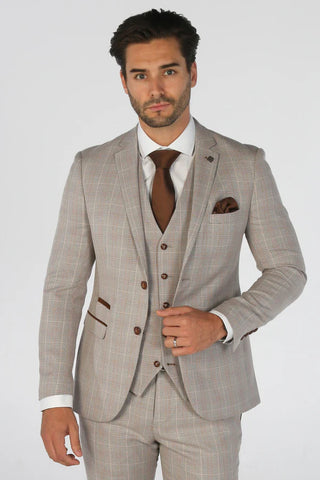 Man wearing a beige checkered suit with a white shirt and brown tie on a light gray background