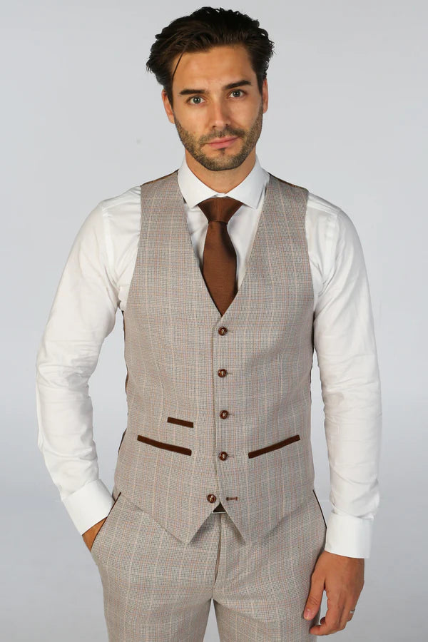 Man wearing a beige checkered vest over a white shirt with a brown tie on a plain background