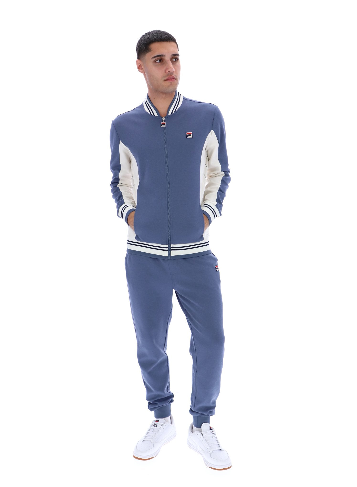 Man wearing a blue tracksuit with white accents on a white background