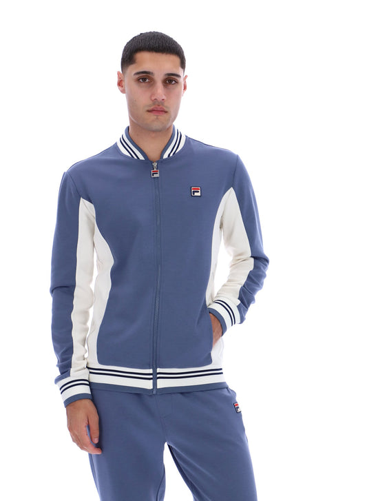 Man wearing a blue and white tracksuit with a visible brand logo on a white background