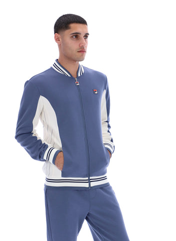Man wearing a blue and white tracksuit with a visible brand logo on a white background