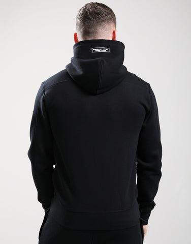 Person wearing a black hoodie with a visible brand logo on the back against a white background