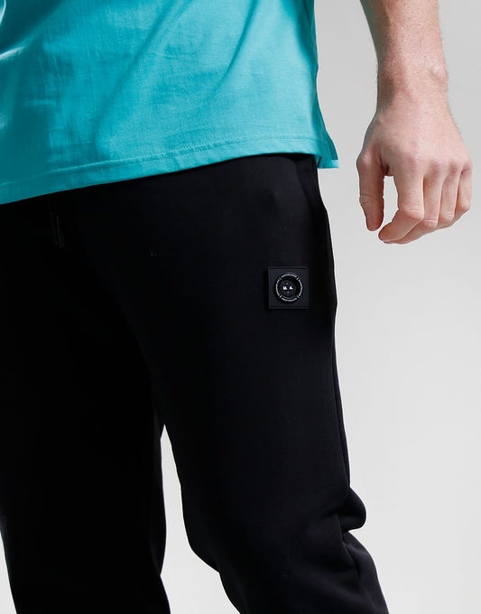 Person wearing black pants with a patch on a light gray background