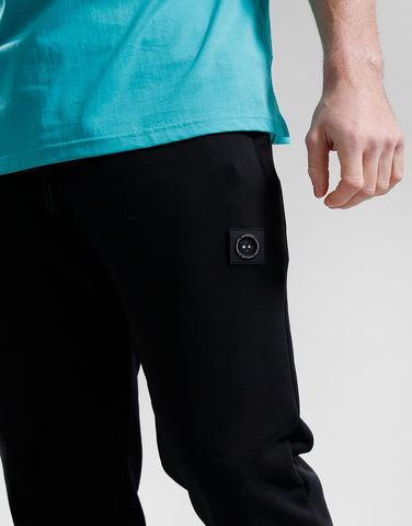 Person wearing black pants with a patch on a light gray background