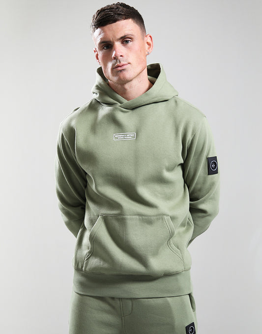Man wearing a green hoodie with brand logos on a light gray background