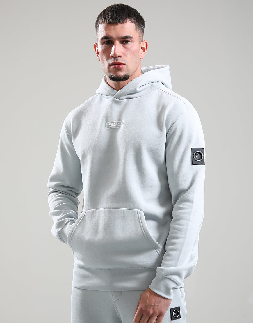 Man wearing a light gray hoodie with brand logos on a plain background