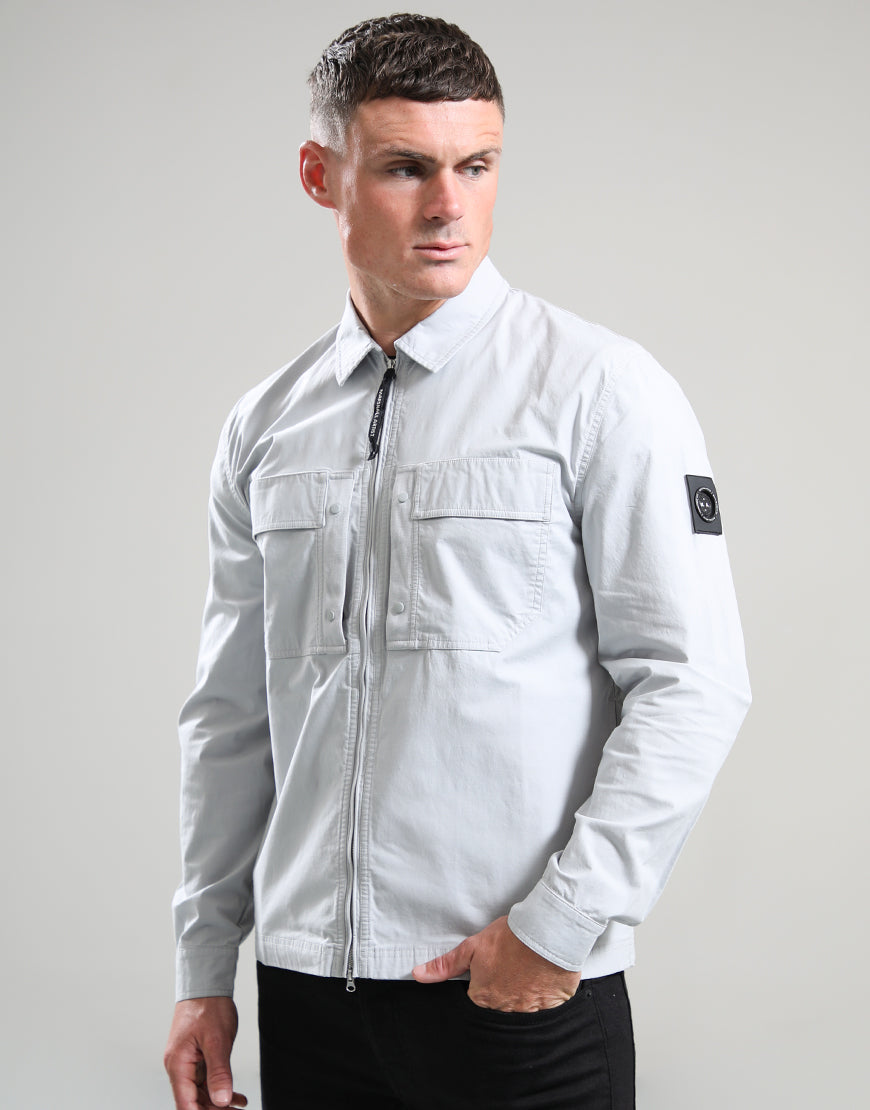 Man wearing a light gray jacket with a brand logo on a plain background