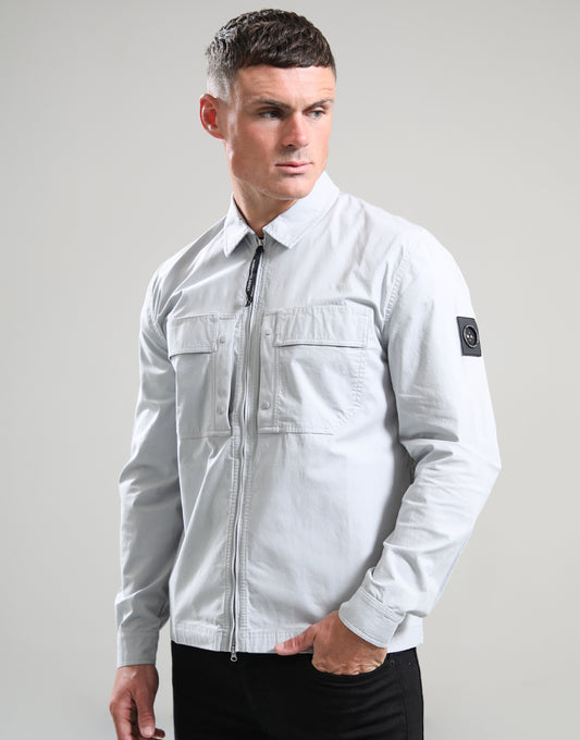 Man wearing a light gray jacket with a brand logo on a plain background