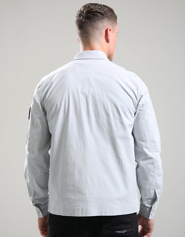 Man wearing a light gray long-sleeve shirt against a plain background