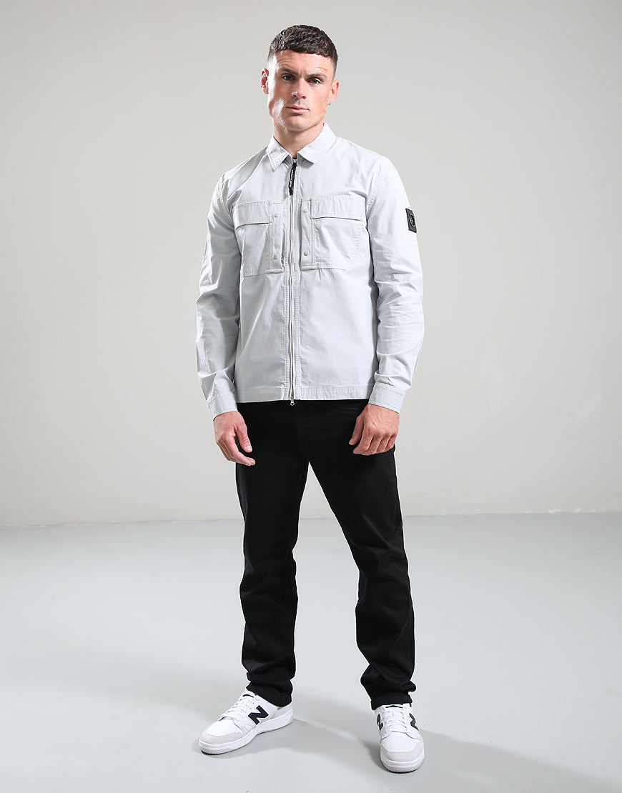 Man wearing a light gray jacket, black pants, and white sneakers on a gray background