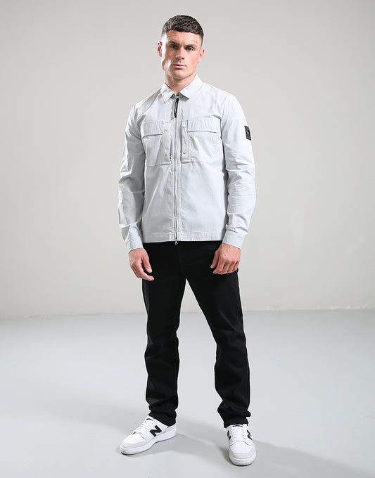 Man wearing a light gray jacket, black pants, and white sneakers on a gray background