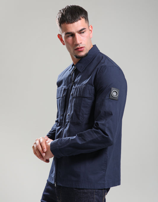 Man wearing a navy blue jacket with a brand logo on a gray background