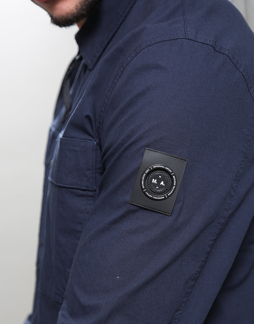 Navy blue shirt with a brand logo patch on the sleeve against a white background