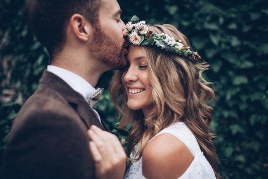 Man and woman embracing with a floral wreath on a green leafy background